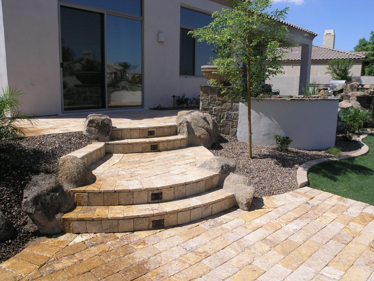 Travertine paver steps and curved patio with natural boulders, desert xeriscape and modern stucco home exterior