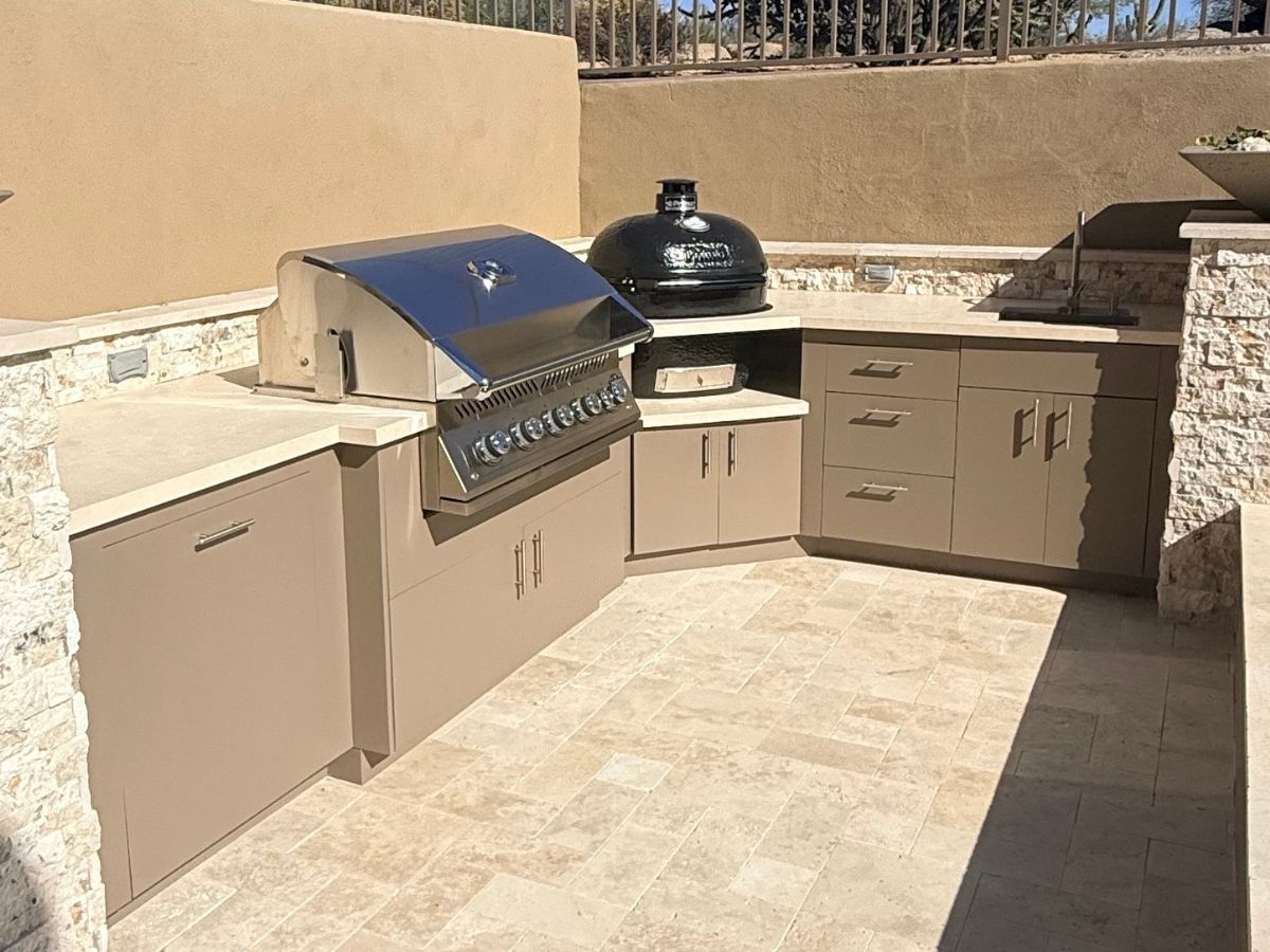 Modern outdoor kitchen with built-in stainless grill, kamado ceramic cooker, beige cabinets and stone countertops