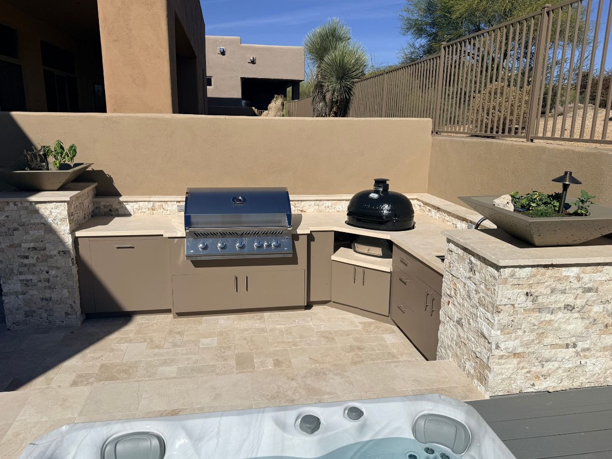 Outdoor kitchen with built-in stainless gas grill, ceramic kamado, stone countertops and hot tub edge