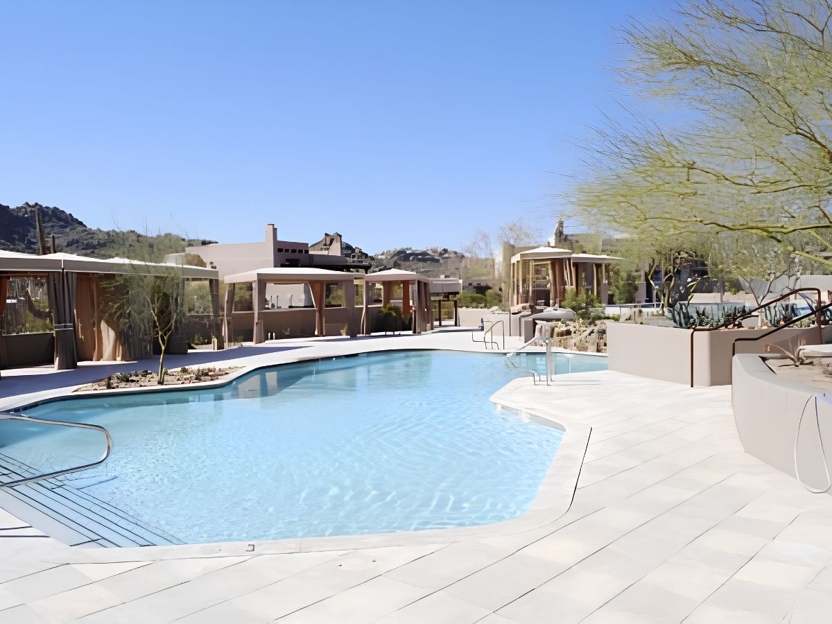 Luxury resort outdoor swimming pool with cabanas, desert landscaping and clear blue sky