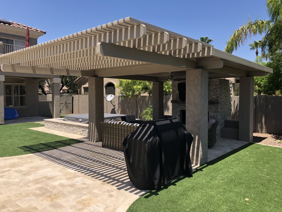 Backyard pergola covered patio with wicker seating, covered grill, outdoor fireplace and artificial turf