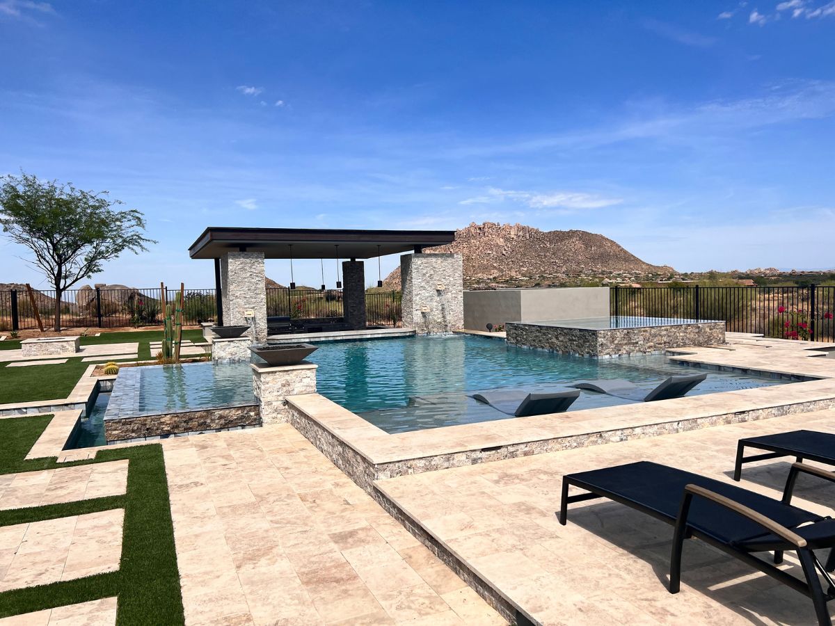 Luxury resort-style backyard pool with swim-up loungers, stone cabana and desert mountain view