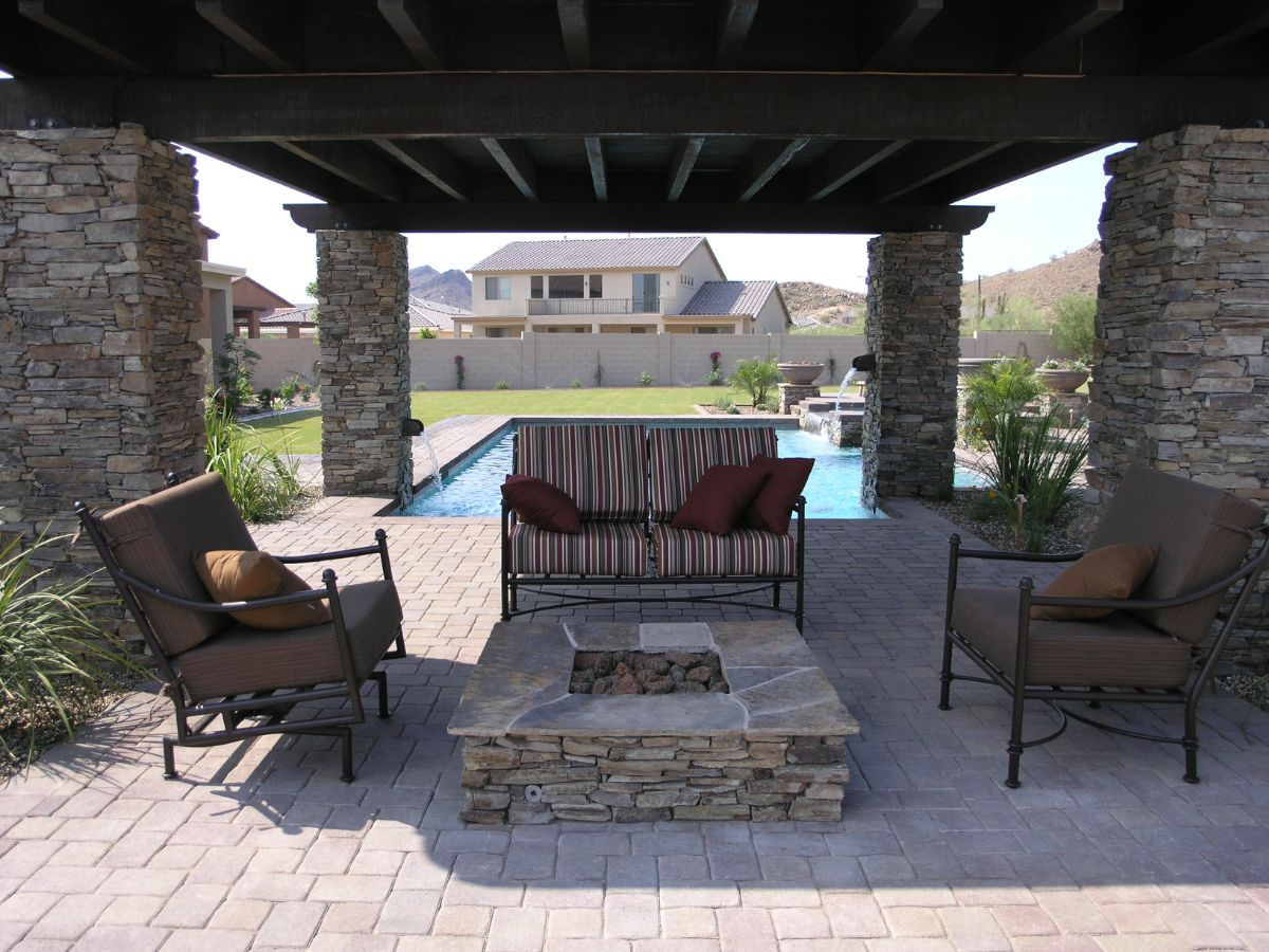 Backyard pool patio with covered pergola, stone columns, outdoor seating and fire pit