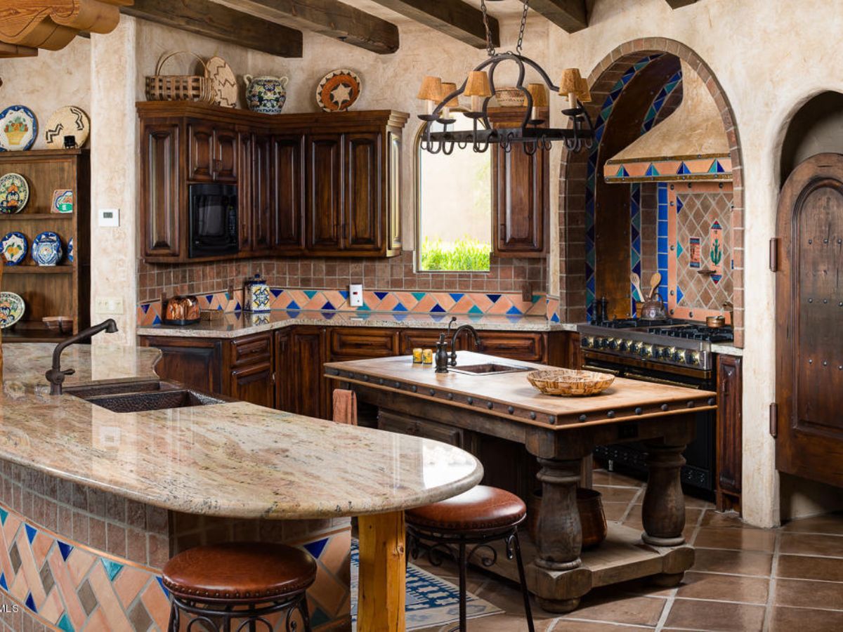Tuscan Mediterranean kitchen with dark wood cabinets, stone countertops, tiled backsplash, island, wood beams