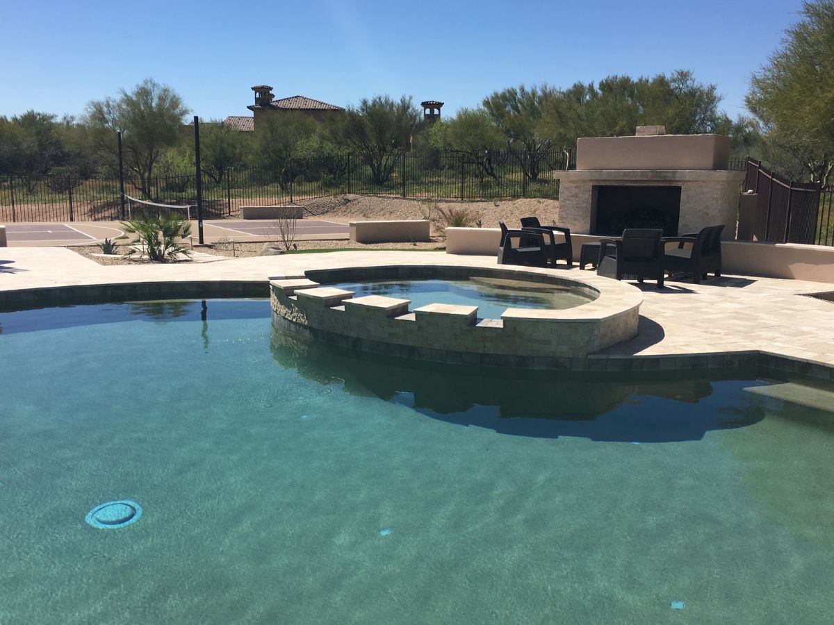 Luxury backyard pool with raised circular spa, stone patio, outdoor fireplace and desert landscaping
