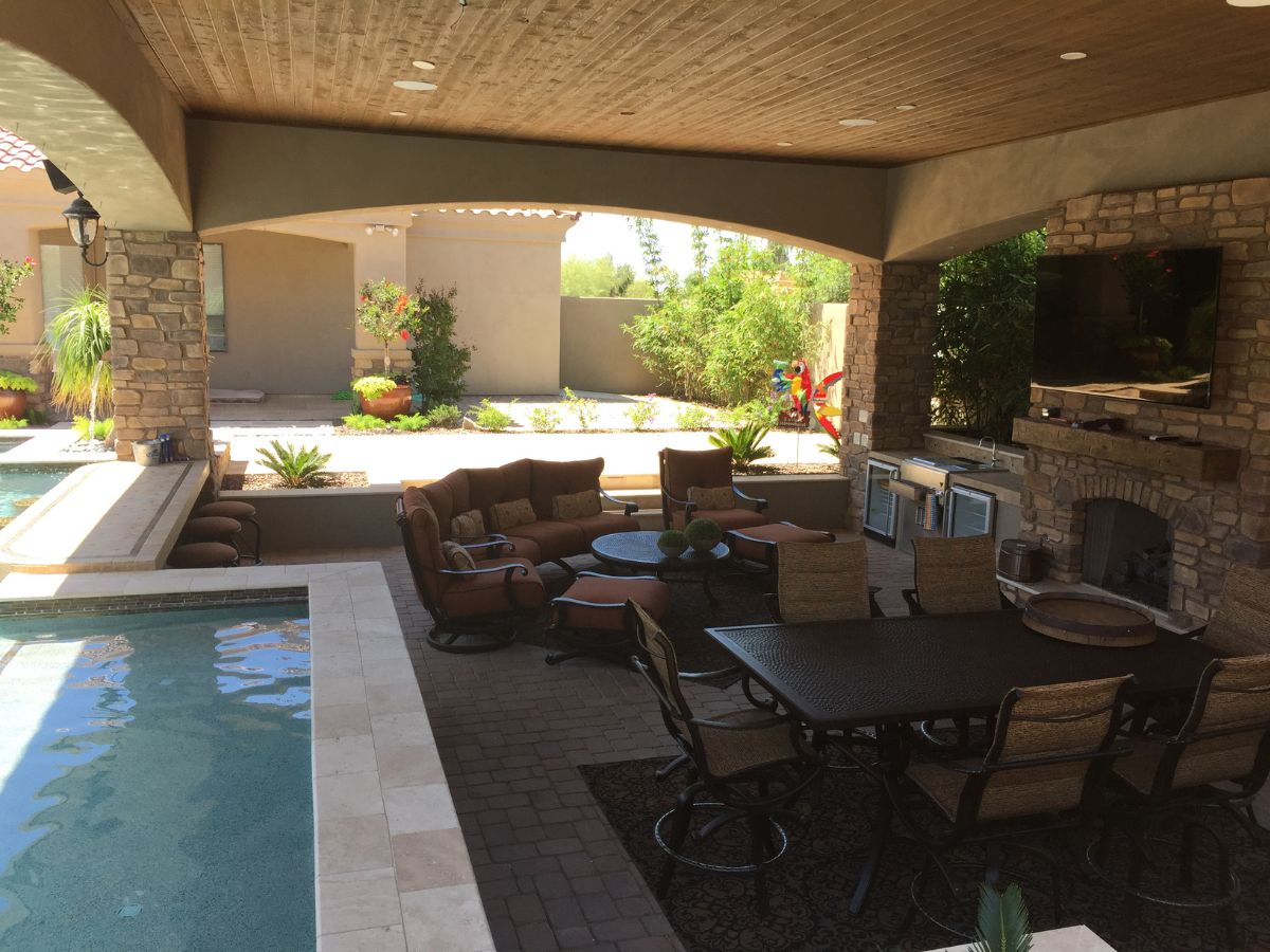 Luxury covered patio with pool, stone fireplace, outdoor dining table, lounge seating and built-in grill