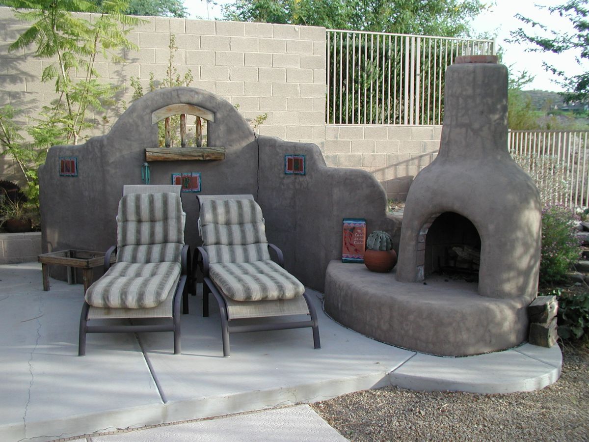 Southwestern outdoor patio with two striped lounge chairs, stucco kiva fireplace, decorative wall and potted cactus