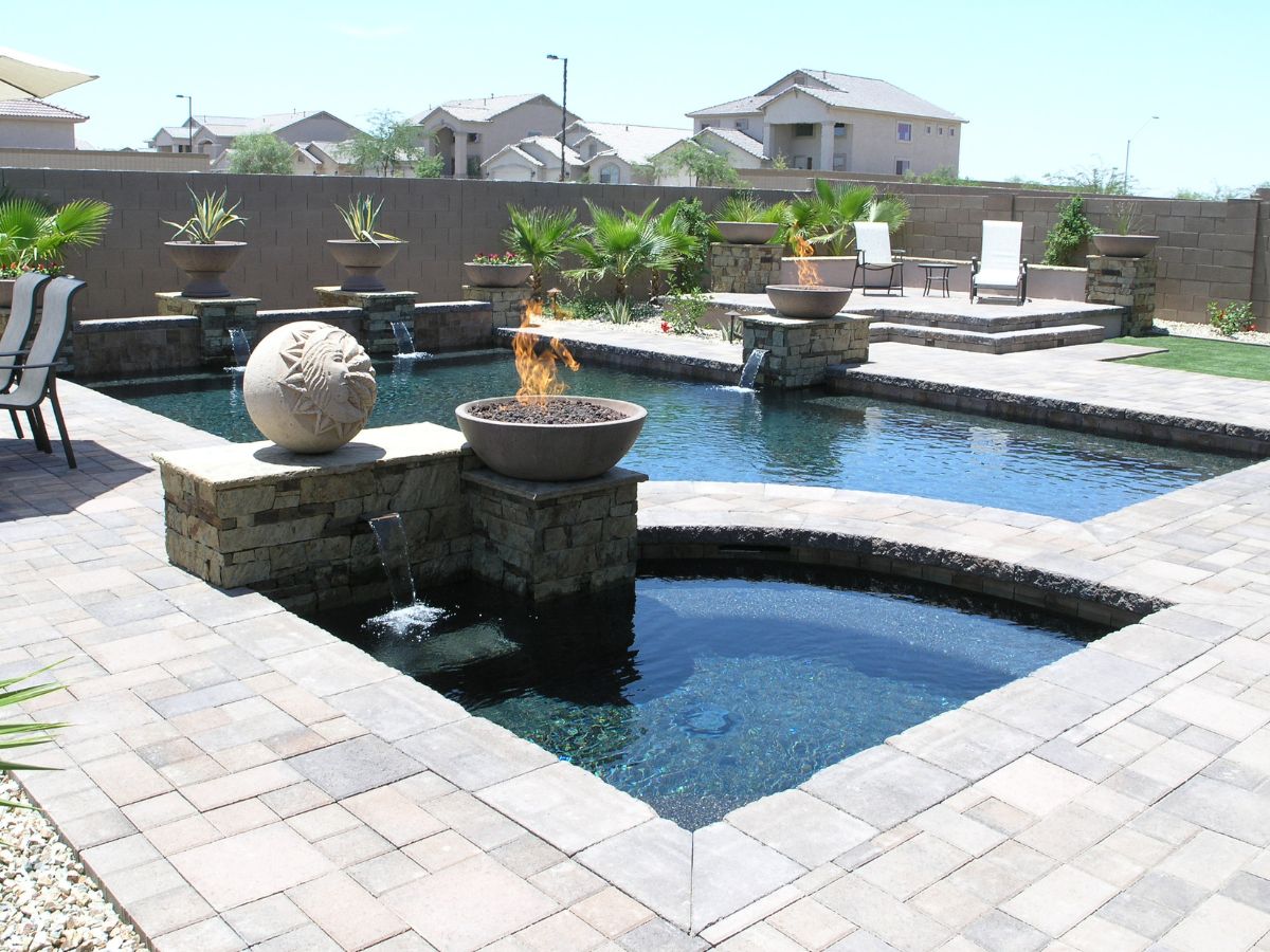 Luxury backyard pool and spa with stone pavers, fire bowls, cascading water features and lounge chairs