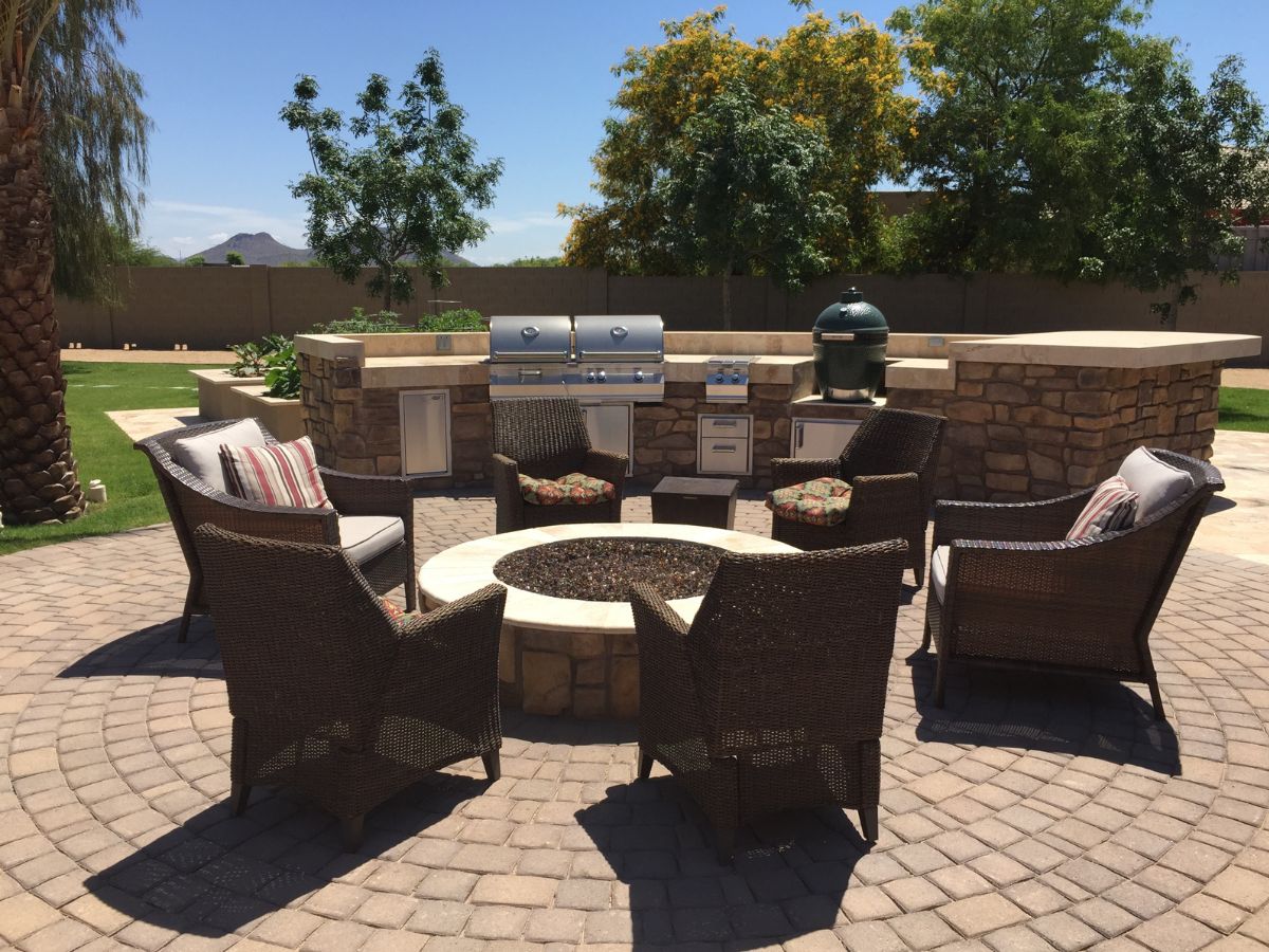 Outdoor patio fire pit with wicker seating, built-in grill and BBQ island in sunny backyard
