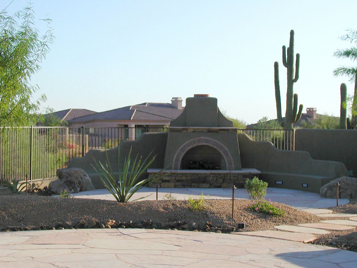 Southwestern desert backyard patio with kiva-style outdoor fireplace, saguaro cactus and xeriscape landscaping