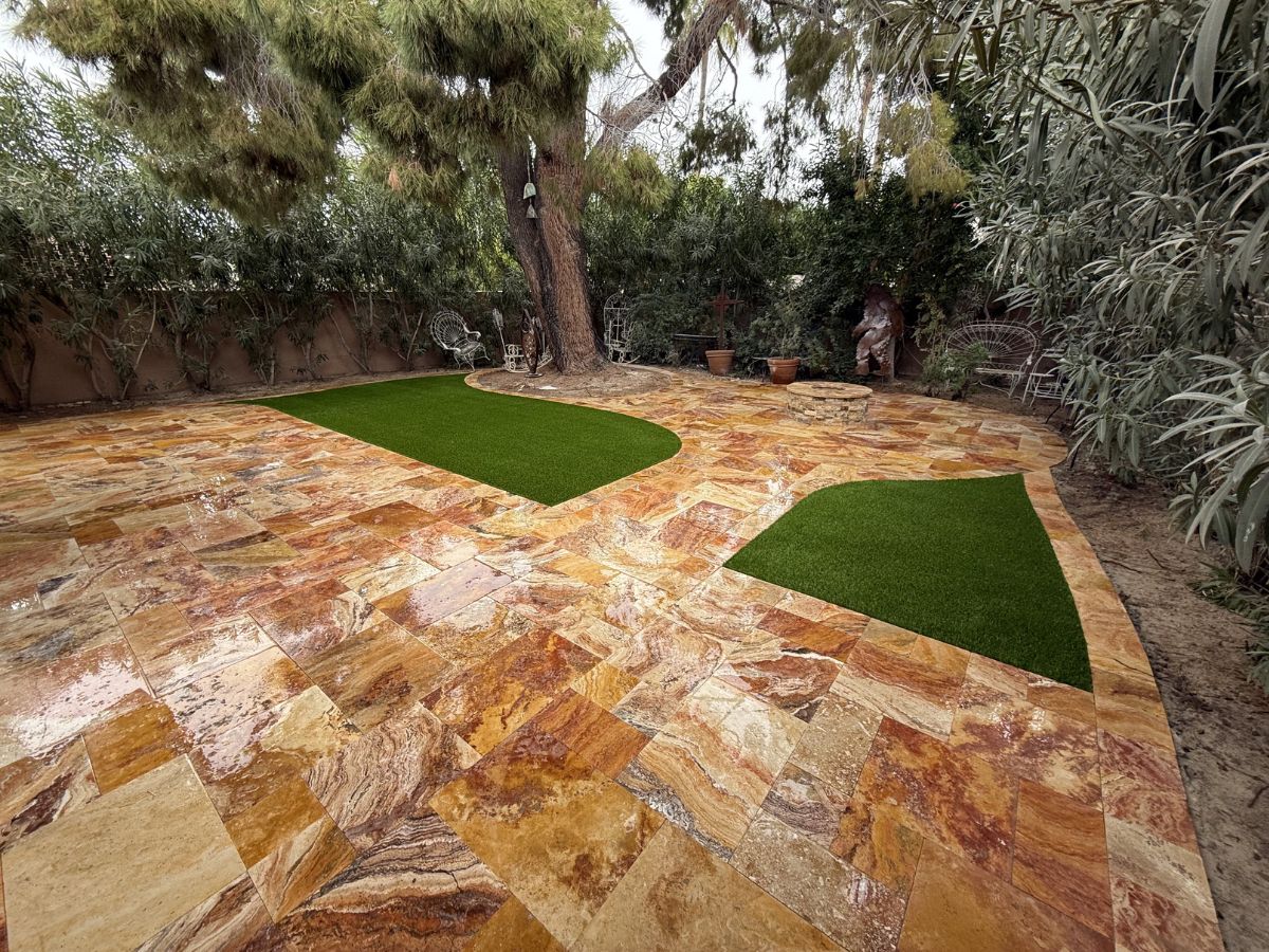 Backyard patio with polished natural stone pavers, artificial turf insets, mature tree and rustic seating area