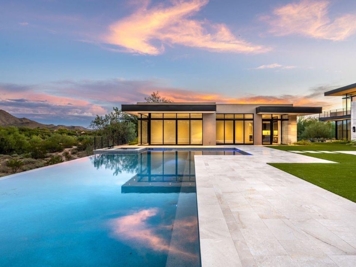 Luxury modern home with infinity pool, glass walls and sweeping desert sunset view