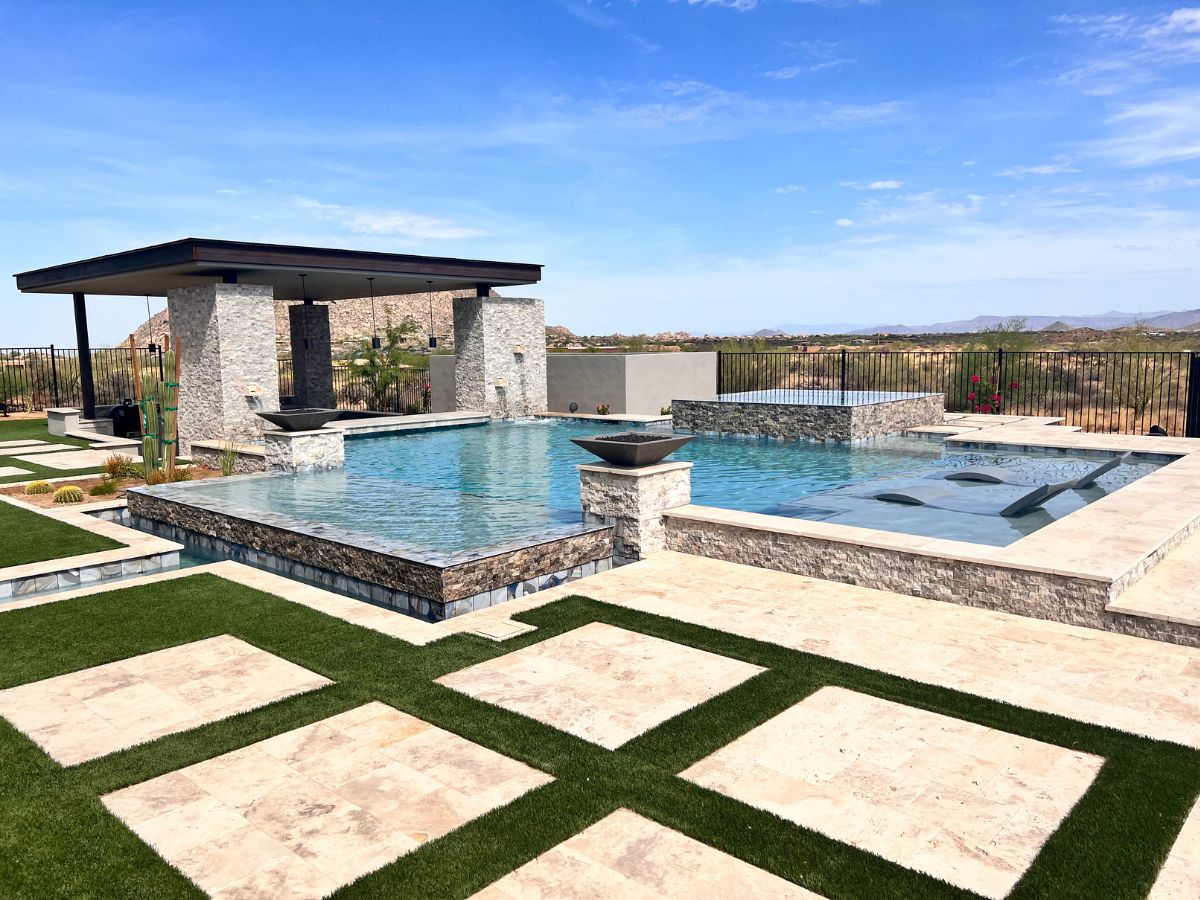 Modern luxury backyard pool with infinity edge, built-in spa, stone decking, shaded pergola and desert mountain view