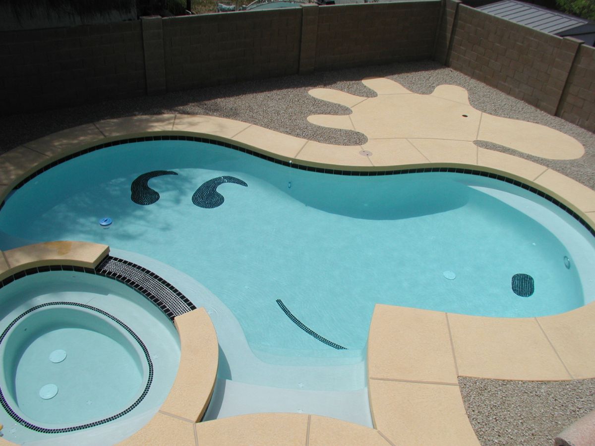 Curved backyard swimming pool and circular spa with light blue water, beige concrete deck and decorative black tile accents.