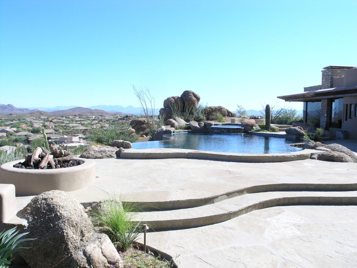 Desert luxury backyard with infinity-style pool, stone patio, fire pit and mountain views