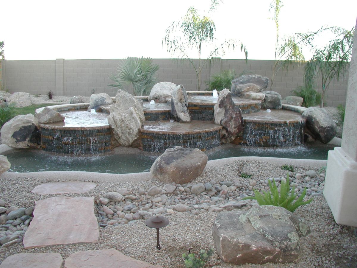 Backyard tiered rock water feature and pond with boulders, stone path and desert landscaping