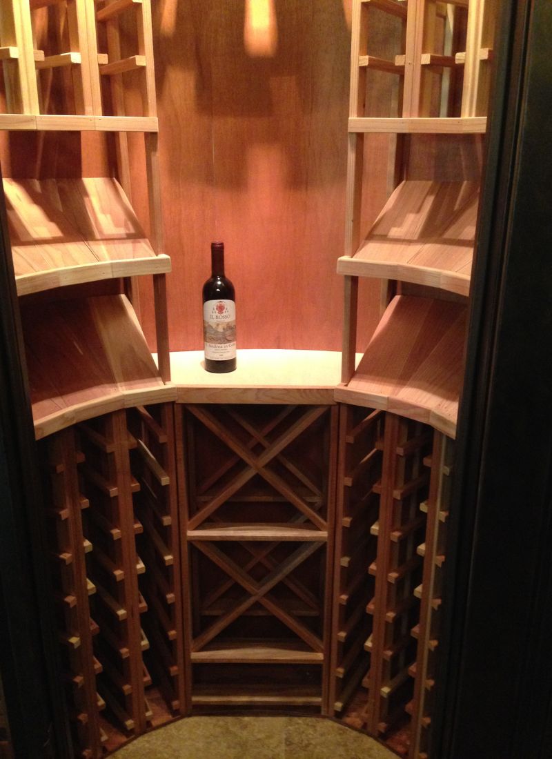 Custom wooden wine cellar storage with curved racks and single red wine bottle on center display shelf