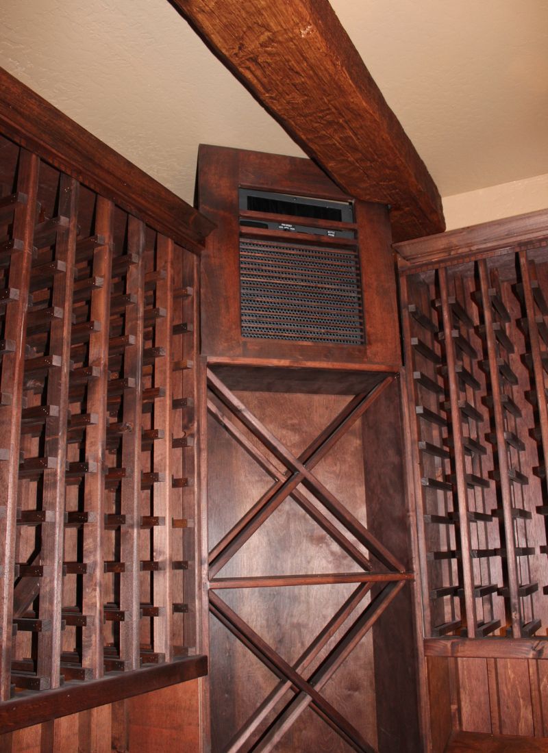 Rustic wine cellar with built-in wooden wine racks, X-shaped bottle storage and ceiling cooling unit