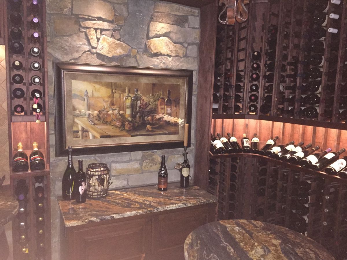 Home wine cellar with stone wall, framed still-life painting, granite countertop and wooden racks of wine bottles